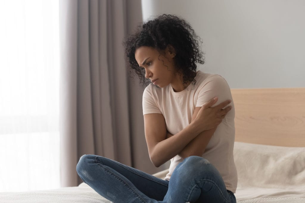 frustrated black girl thinking of loneliness, hurt, sitting on bed looking for therapist in Atlanta, GA